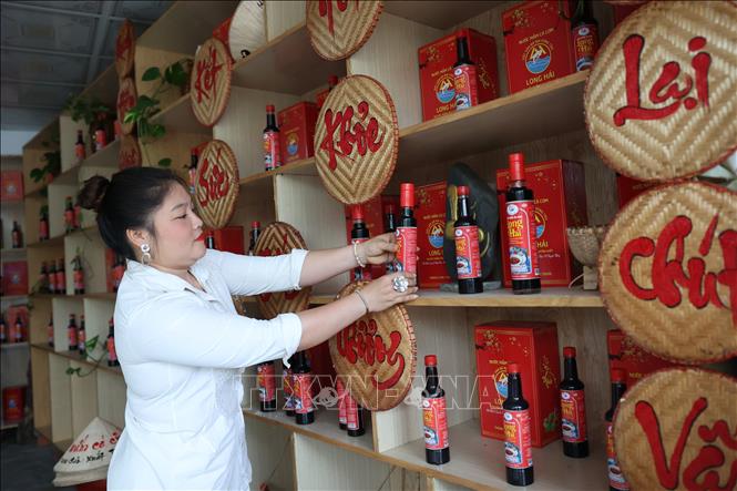 Chị Nguyễn Thị Chiến, Giám đốc Công ty TNHH Sản xuất – Thương mại và Dịch vụ Hati, sắp xếp lại gian hàng trưng bày nước mắm truyền thống ngay tại cơ sở sản xuất. Ảnh: Hoàng Nhị - TTXVN.
