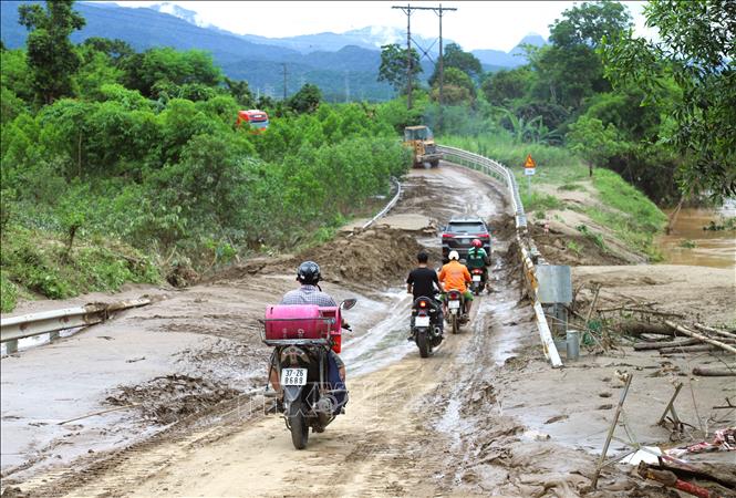 Người dân điều khiển phương tiện ô tô, xe máy di chuyển qua một điểm ngập trên quốc lộ 7 vừa thông tuyến tạm thời vào trưa ngày 24/7. Ảnh: Xuân Tiến - TTXVN 