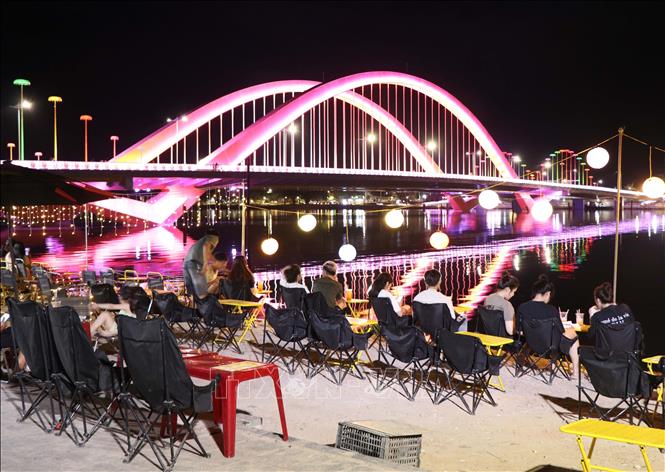 Visitors enjoy a cool night with the view of Nguyen Hoang Bridge. VNA Photo: Nguyên Lý