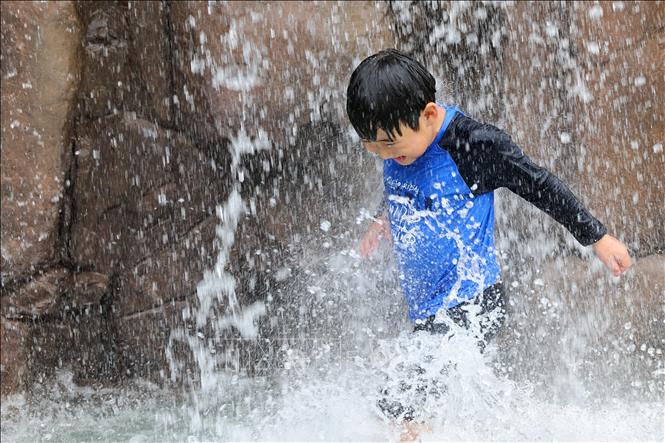 Em nhỏ làm mát dưới đài phun nước ở Incheon, Hàn Quốc ngày 13/7/2025. Ảnh: YONHAP/TTXVN