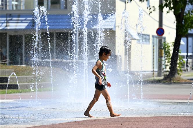 Em nhỏ làm mát dưới đài phun nước khi nhiệt độ chạm ngưỡng 40 độ C ở Obihiro, Hokkaido, Nhật Bản ngày 24/7/2025. Ảnh: Kyodo/TTXVN