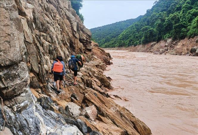 Tổ công tác vất vả di chuyển theo vách đá ngược thượng nguồn sông Nậm Mộ trên hành trình tiếp cận bản Cha Nga (xã Mỹ Lý, tỉnh Nghệ An). Ảnh: TTXVN phát 
