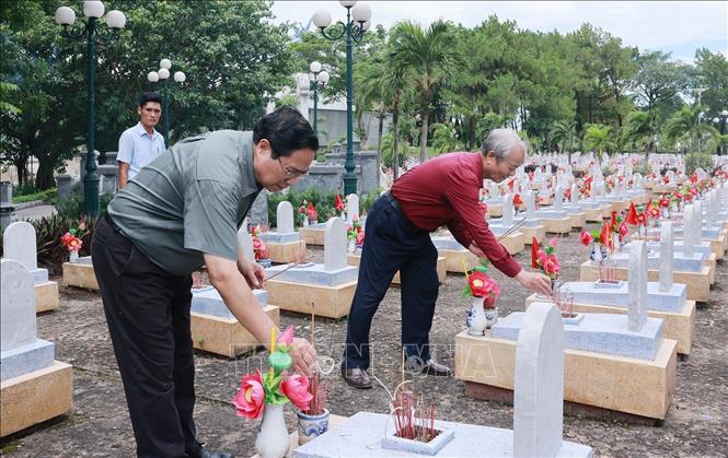 Thủ tướng Phạm Minh Chính thắp hương trên phần mộ liệt sĩ tại Nghĩa trang liệt sĩ Quốc gia Đường 9. Ảnh: Dương Giang-TTXVN 

