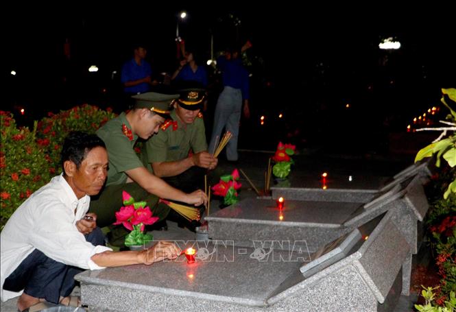 Gia đình liệt sỹ và đoàn viên cùng thắp hương, thắp nến tri ân tại Nghĩa trang liệt sĩ tỉnh Vĩnh Long. Ảnh: Lê Thúy Hằng – TTXVN