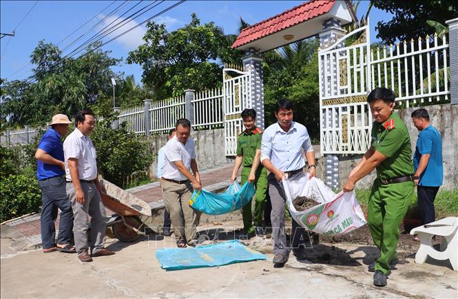Các lực lượng cùng tham gia hỗ trợ gia đình Bà Mẹ Việt Nam anh hùng Nguyễn Thị Bảy, xã Song Phú, tỉnh Vĩnh Long dọn dẹp nhà cửa nhân dịp 27/7. Ảnh: Lê Thúy Hằng – TTXVN. 
