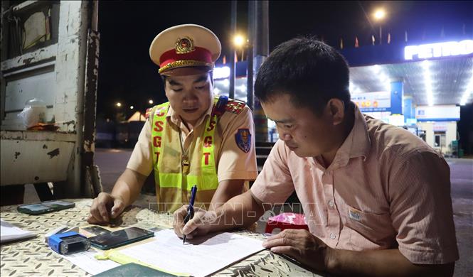 Lực lượng Cảnh sát giao thông trạm Đồng Phú lập biên bản, xử lý xe khách vi phạm giao thông. Ảnh: Đậu Tất Thành – TTXVN