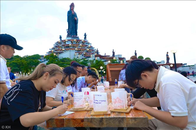 Người dân viết những dòng nguyện cầu vào hoa đăng tại khu vực tượng Phật bà trên đỉnh núi Bà Đen. Ảnh: Thành Phương – TTXVN