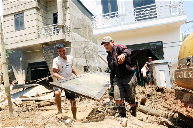 Vận chuyển đồ dùng, vật dụng ra ngoài để nhanh chóng thu dọn bùn đất trôi vào nhà các hộ dân của xã Chiềng Sơ. Ảnh: Quang Quyết - TTXVN