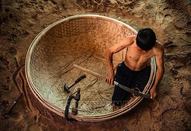 To shape the boat, a round hole is dug into the ground, where the woven bamboo base is placed for further shaping. VNA Photo: Khánh Hòa 