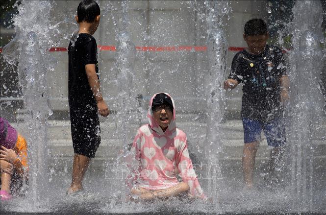 Các em nhỏ chơi đùa bên đài phun nước để tránh nóng tại Seoul, Hàn Quốc. Ảnh: THX/TTXVN