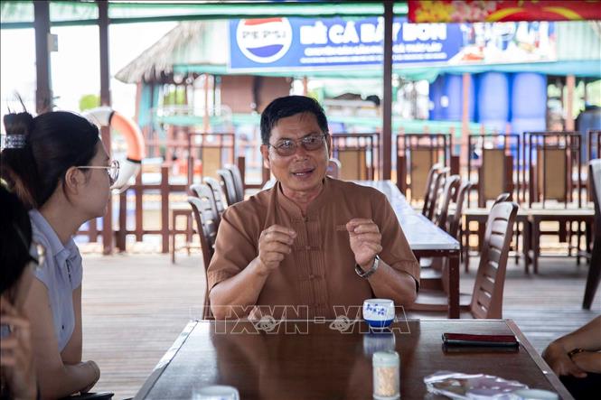 Ông Bảy Bon chia sẻ câu chuyện về hành trình xây dựng bè cá và phát triển mô hình du lịch cộng đồng Cồn Sơn cho du khách tham quan. Ảnh: Thanh Liêm - TTXVN