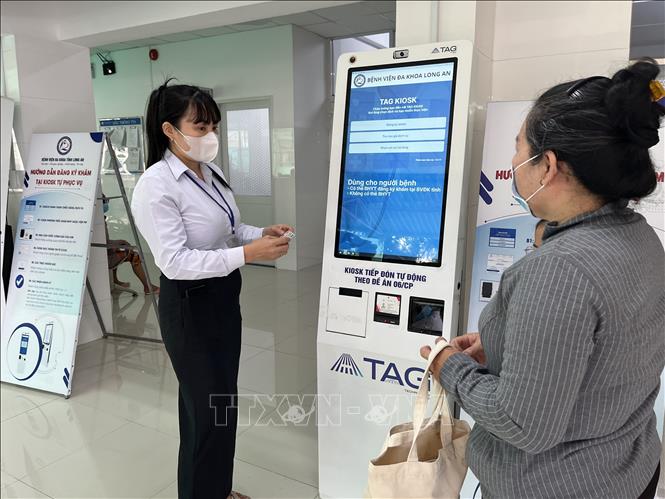 Nhân viên Bệnh viện đa khoa Long An hướng dẫn người dân sử dụng Kiosk tự phục vụ - đăng ký khám chữa bệnh qua máy tự động. Ảnh: Đức Hạnh - TTXVN