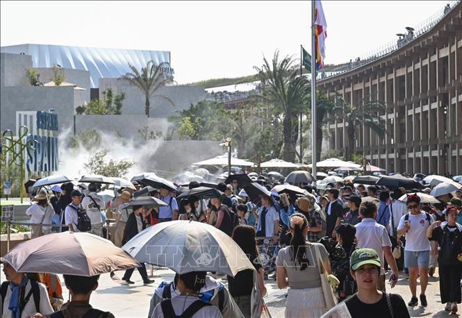 Người dân dùng ô che nắng khi tham quan một triển lãm ở Osaka, Nhật Bản. Ảnh: Kyodo/TTXVN