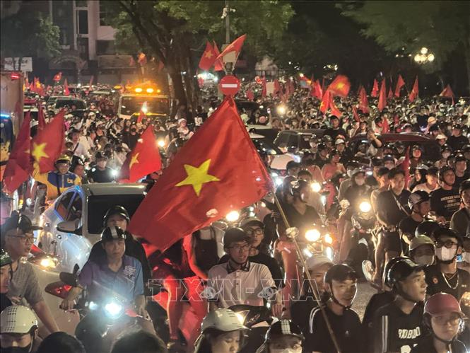 Người dân mang theo cờ Tổ quốc diễu hành trên các tuyến phố Hà Nội để mừng chiến thắng. Ảnh: Minh Quyết - TTXVN