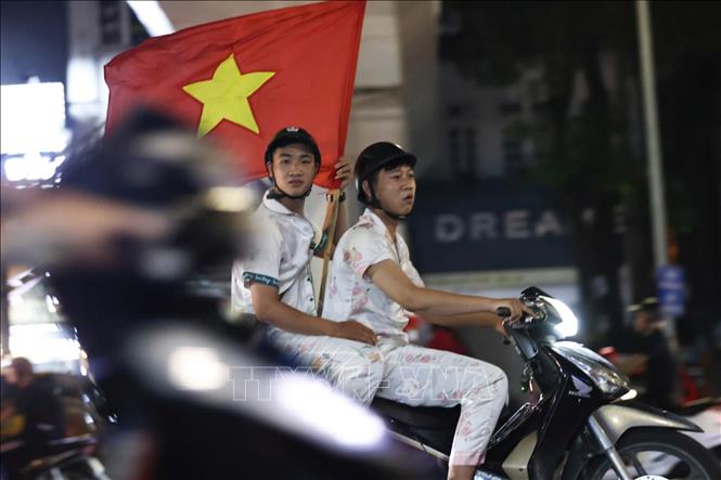 Người dân mang theo cờ Tổ quốc diễu hành trên các tuyến phố Hà Nội ăn mừng chiến thắng. Ảnh: Thanh Tùng - TTXVN