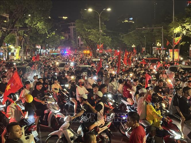 Người dân mang theo cờ Tổ quốc diễu hành trên các tuyến phố Hà Nội để mừng chiến thắng. Ảnh: Minh Quyết - TTXVN