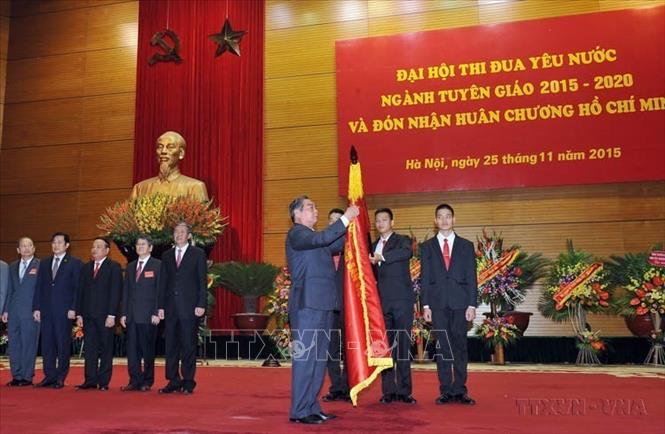  Thường trực Ban Bí thư Lê Hồng Anh gắn Huân chương Hồ Chí Minh lên lá cờ truyền thống ngành Tuyên giáo tại Đại hội Thi đua yêu nước ngành Tuyên giáo, giai đoạn 2015 - 2020 (25/11/2015). Ảnh: Trọng Đức - TTXVN