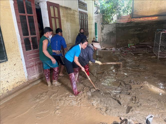Lực lượng tình nguyện hỗ trợ các gia đình dọn vệ sinh sau lũ. Ảnh: TTXVN phát