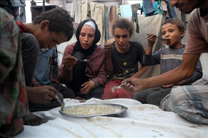 Một gia đình người Palestine dùng bữa ăn được viện trợ tại trại tị nạn ở thành phố Gaza, ngày 29/7/2025. Ảnh: THX/TTXVN 