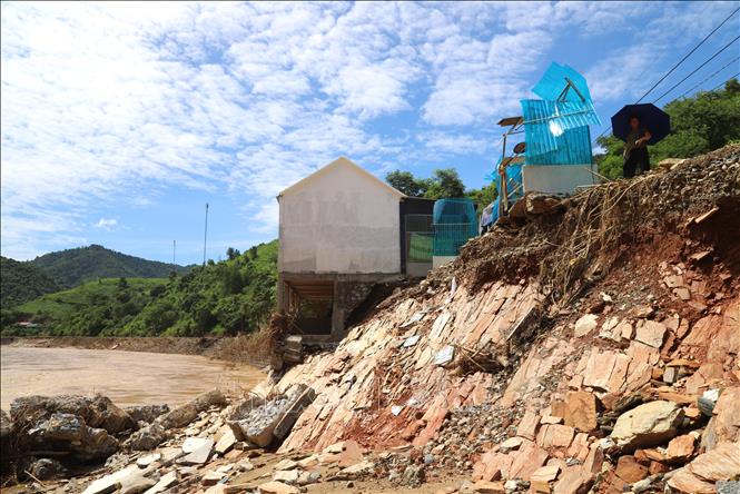 Lũ dữ phá vỡ bờ kè sông, cuốn trôi toàn bộ một ngôi nhà, nền móng và hàng ngàn khối đất, đá, ngôi nhà còn lại nằm chênh vênh và nguy cơ sạt lở rất cao. Ảnh: Xuân Tiến - TTXVN 