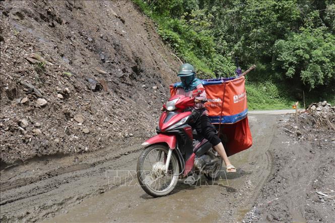 Người dân liều mình vượt qua đoạn đường lầy lội, sạt lở Km63 + 64 trên Quốc lộ 34. Ảnh: Minh Tâm-TTXVN