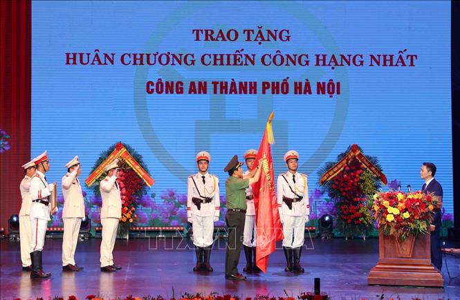 Đại tướng Lương Tam Quang, Bộ trưởng Bộ Công an gắn Huân chương Chiến công hạng Nhất lên lá cờ truyền thống của Công an thành phố Hà Nội. Ảnh: Phạm Kiên - TTXVN