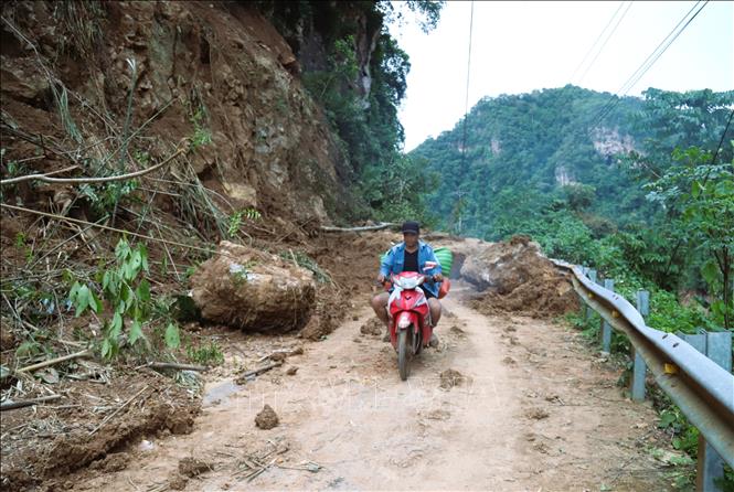 Bất chấp hiểm nguy, người dân phải khó nhọc, vất vả hàng chục phút mới lách qua được những khe nhỏ kẹt giữa những tảng đá lớn để đi hơn 20km nhận nhu yếu phẩm, lương thực cứu trợ, tiếp tế từ các đoàn thiện nguyện. Ảnh: Xuân Tiến - TTXVN 
