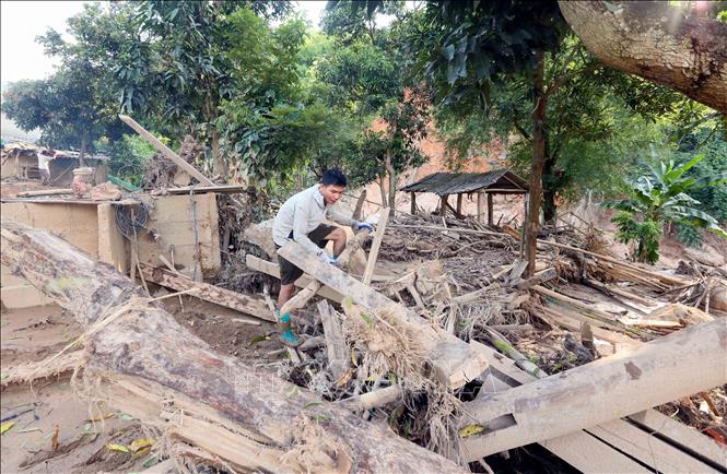 Anh Quàng Văn Biên, bản Huổi Sài, xã Chiềng Sơ thu dọn cành cây, củi bị lũ trôi vào nhà. Ảnh: Quang Quyết - TTXVN