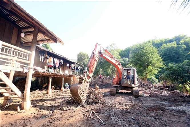Hỗ trợ nhân dân bản Huổi Sài, xã Chiềng Sơ thu dọn đất, đá, cây tràn vào nhà sau trận lũ ống, lũ quét. Ảnh: Quang Quyết - TTXVN