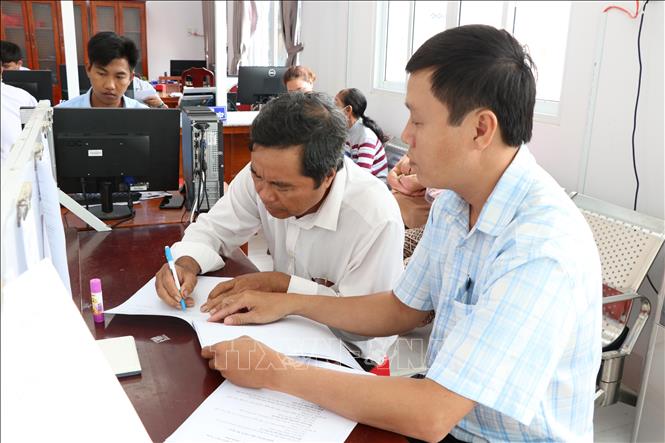Người dân thực hiện thủ tục hành chính tại Trung tâm Phục vụ hành chính công xã Vinh Kim. Ảnh: Thanh Hòa - TTXVN