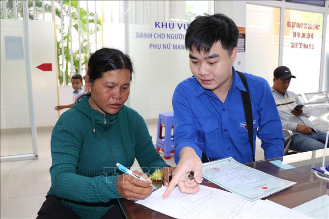 Anh Trần Lê Viễn Thông, Bí thư chi đoàn khóm 3, phường Trà Vinh hỗ trợ người dân thực hiện thủ tục hành chính tại Trung tâm Phục vụ hành chính công phường Trà Vinh. Ảnh: Thanh Hòa - TTXVN