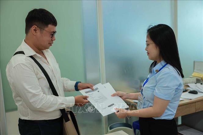 Nhân viên bưu điện hỗ trợ người dân in ấn tài liệu miễn phí để nộp hồ sơ, qua đó tiết kiệm thời gian, chi phí. Ảnh: Hoàng Hiếu - TTXVN
