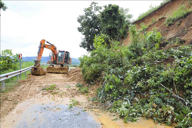 Đơn vị thi công tiến hành san gạt các điểm sạt lở trên quốc lộ 12. Ảnh: TTXVN