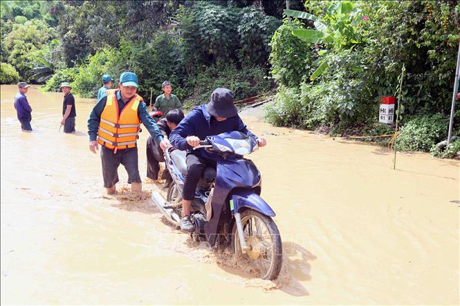 Hỗ trợ người dân ra khỏi vùng ngập lụt tại xã Mường Hung. Ảnh: Quang Quyết - TTXVN