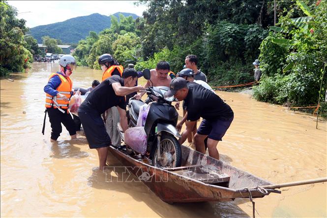 Hỗ trợ người dân ra khỏi vùng ngập lụt tại xã Mường Hung. Ảnh: Quang Quyết - TTXVN
