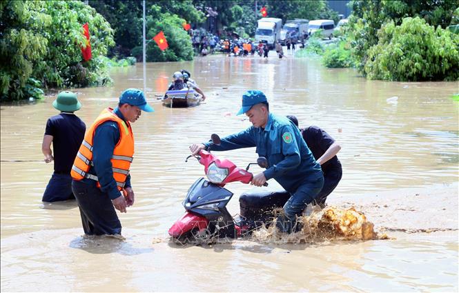 Hỗ trợ người dân ra khỏi vùng ngập lụt tại xã Mường Hung. Ảnh: Quang Quyết - TTXVN