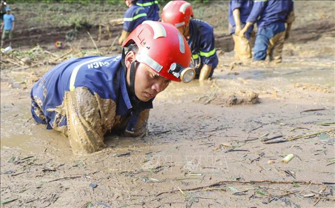 Các chiến sĩ ngâm mình trong bùn đất để tìm kiếm nạn nhân mất tích. Ảnh: Xuân Tư - TTXVN