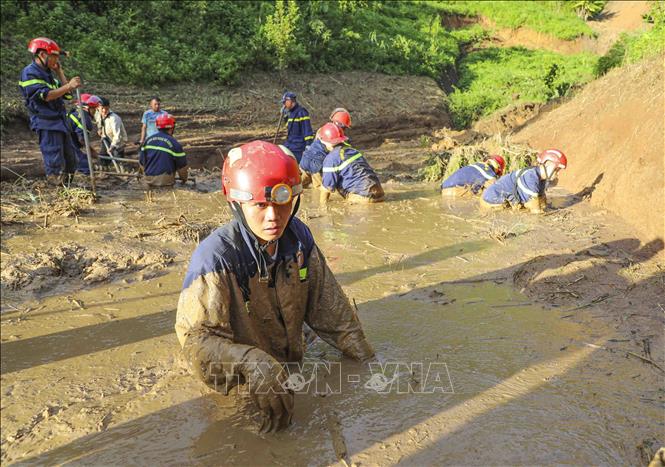 Các chiến sĩ ngâm mình trong bùn đất để tìm kiếm nạn nhân mất tích. Ảnh: Xuân Tư - TTXVN