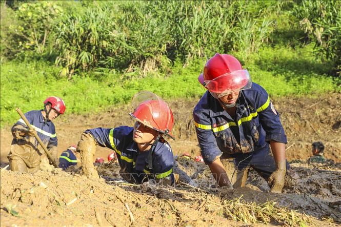 Các chiến sĩ Phòng cháy chữa cháy và Cứu nạn cứu hộ ngâm mình trong bùn đất để tìm kiếm các nạn nhân. Ảnh: Xuân Tư - TTXVN