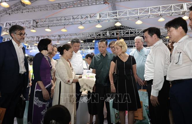 Các đại biểu tham quan gian trưng bày sản phẩm vải dệt từ tơ sen. Ảnh: Trần Việt - TTXVN 