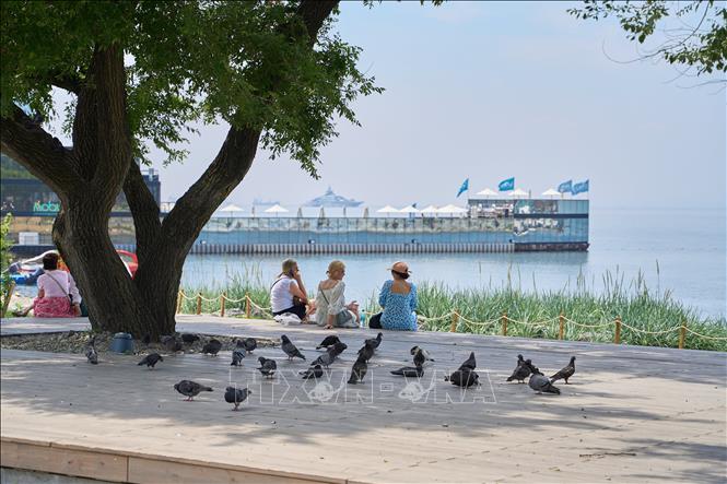 Khách du lịch ngồi nghỉ dưới bóng râm tại Vladivostok, Nga. Ảnh: THX/TTXVN