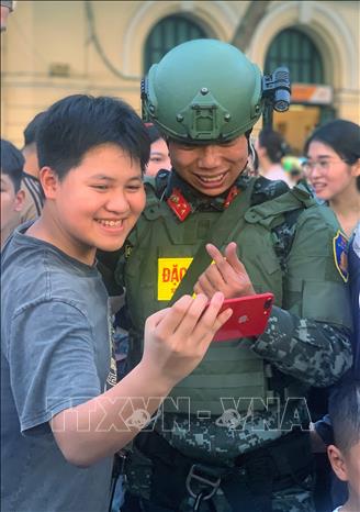 Người dân thích thú chụp ảnh cùng chiến sĩ Cảnh sát đặc nhiệm. Ảnh: Tuấn Đức - TTXVN