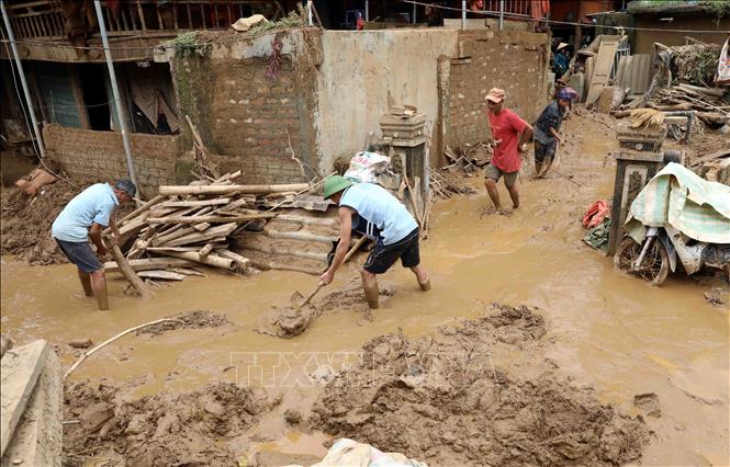 Người dân và lực lượng chức năng tích cực dọn dẹp bùn đất, vệ sinh nhà cửa. Ảnh: Trung Kiên - TTXVN