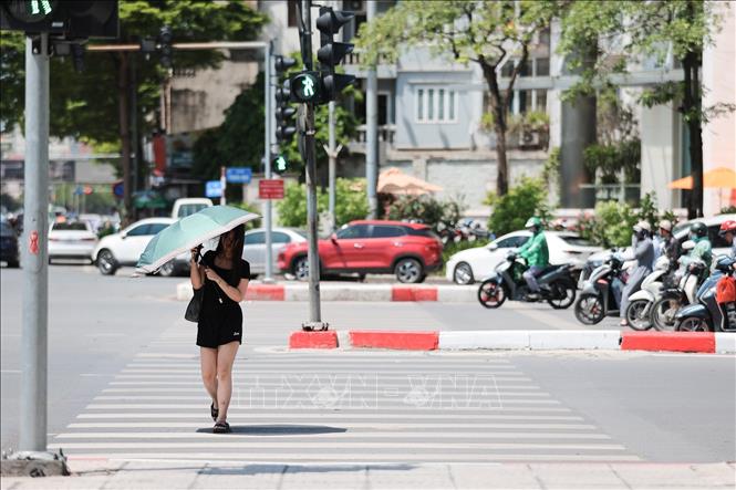 Người dân sử dụng ô khi di chuyển trên phố dưới trời nắng gay gắt trên 40 độ C. Ảnh: Lê Đông - TTXVN