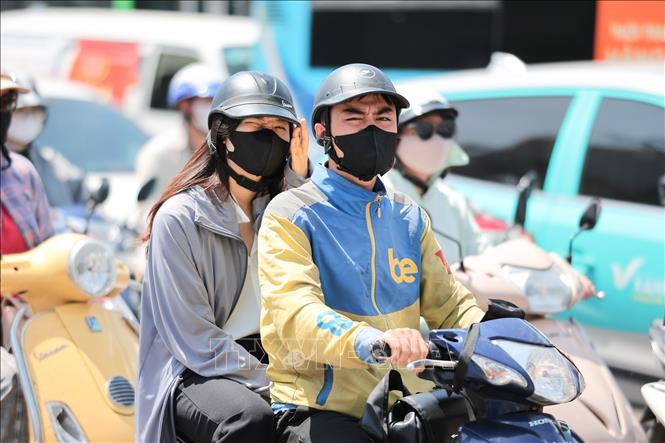 Dù đã sử dụng khẩu trang, áo chống nắng nhưng nhiều người dân tham gia giao thông vẫn cảm thấy khó chịu và oi bức. Ảnh: Lê Đông - TTXVN
