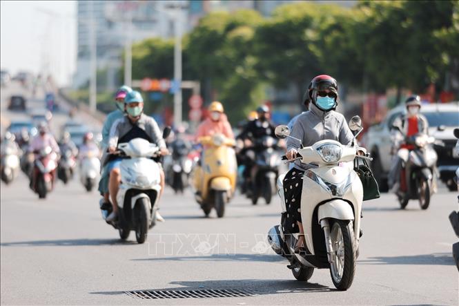 Người dân sử dụng khẩu trang, áo chống nắng giúp tránh nóng bức khi tham gia giao thông. Ảnh: Lê Đông - TTXVN