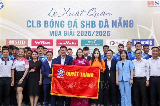 Lãnh đạo thành phố Đà Nẵng và Ban Lãnh đạo Công ty cùng các cầu thủ đội bóng SHB với lá cờ Quyết thắng được ký tên thể hiện quyết tâm đoạt mục tiêu đề ra tại Lễ xuất quân. Ảnh: Trần Lê Lâm – TTXVN