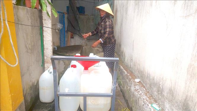 Người dân tại làng chài Minh Hải phải chắt nước ngọt vào từng can để tích trữ và sử dụng. Ảnh: Quang Thái - TTXVN