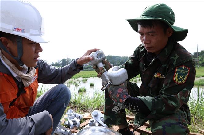 Công nhân Công ty Cổ phần Tập đoàn Đầu tư thương mại công nghiệp Việt Á lắp đặt sứ cách điện trước khi được treo lên vị trí cột số 352, thuộc địa bàn xã Vũ Ninh, tỉnh Phú Thọ. Ảnh: Vũ Sinh - TTXVN