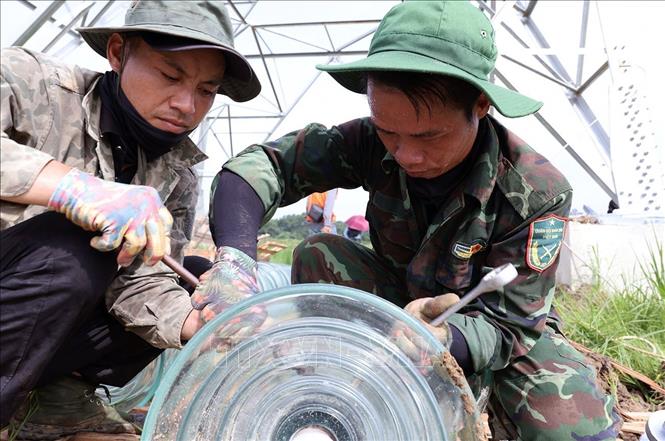 Công nhân Công ty Cổ phần Tập đoàn Đầu tư thương mại công nghiệp Việt Á lắp đặt sứ cách điện trước khi được treo lên vị trí cột số 352, thuộc địa bàn xã Vũ Ninh, tỉnh Phú Thọ. Ảnh: Vũ Sinh - TTXVN